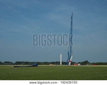 building a new wind power plant with a big blue crane Kalkar Germany