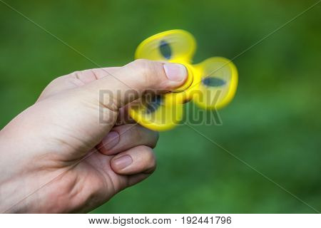 Teenager Is Playing A Yellow Spinner In Her Hand Outdoors.