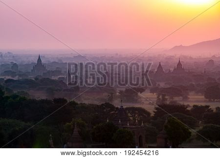 Beautiful ancient pagoda field in sun rise with fog and haze