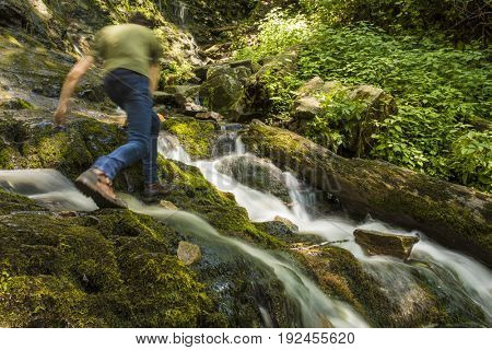Man hiking over waterfall, motion blur from hiking.