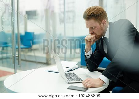 Concentrated salesman looking at laptop display in office