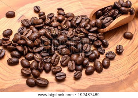 The Roasted Coffee Beans Lie On The Wooden Surface Of Olive Wood With A Scoop