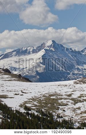 The Summit of Longs Peak as seen from Trail Ridge Road with white puffy clouds in the blue sky