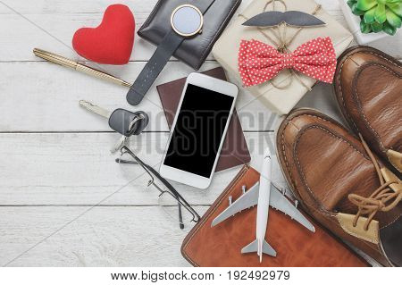 Top view Happy Father day with travel concept.Mobile phone and passport on rustic wooden background. accessories with airplane mustache vintage bow tie pen present white key car shoes and notebook tree.