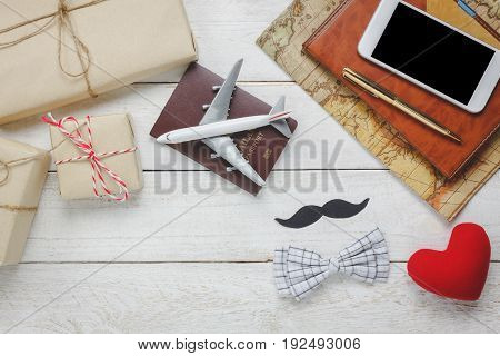 Top view Happy Father day with travel.Airplane and passport on rustic wooden background.accessories with mapmustachevintage bow tiepenpresentred heartwhite mobile phone and notebook.