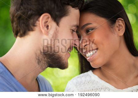 Closeup portrait of smiling young interracial couple touching foreheads