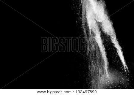 Freeze motion explosion of white dust on black background. By throwing talcum powder out of hand.