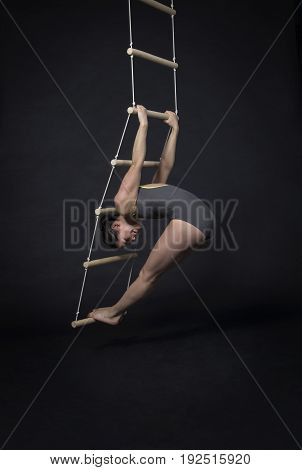 Young,smiling Girl Performs Gymnastic Exercises On A Rope Ladder.
