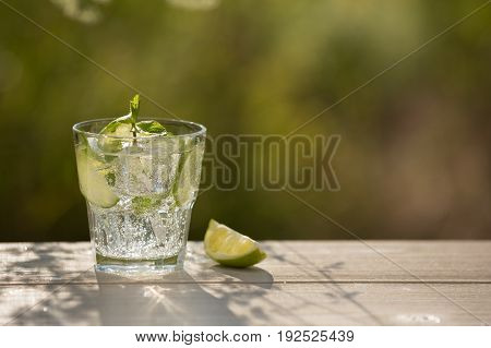 A glass of soda water on an old board on nature ice bubbles grapefruit spike