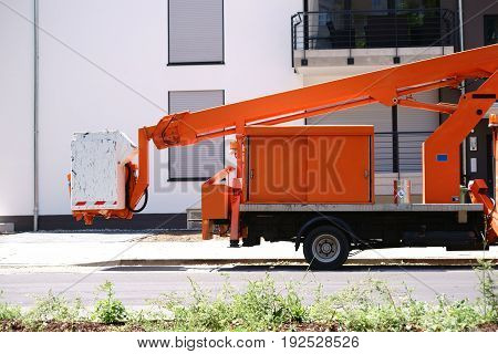 A lifting platform on a small truck stands in front of a modern residential building.