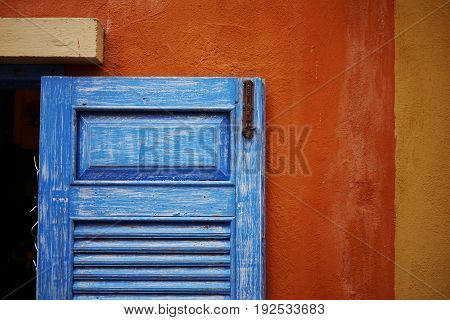 blue wood window with grunge texture on the orange and yellow wall.