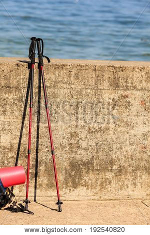 Equipment survival leisure trip holidays concept. Outdoor gear left outside. Bagpack map nordic walking sticks leaning on wall.