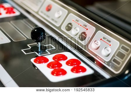Detail of a black joystick and red buttons on an arcade game machine