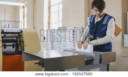 The print operator checks the quality of the finished product, in a printing factory