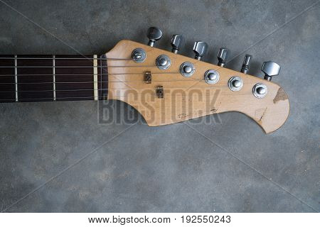 detail of vintage electric guitar headstock on the concrete background.
