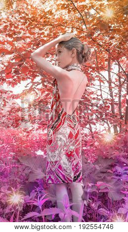 a young girl in a dress with nude backs worth in the foliage in the Woods, Red forest. hair decorated with foliage. in the sunlight.