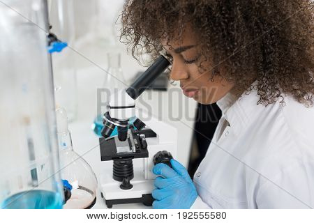 Young Scientist Looking Through Microscope In Laboratory, Mix Race Researcher Doing Research Experiments In Modern Lab