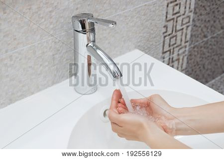 Washing of hands with soap under running water.