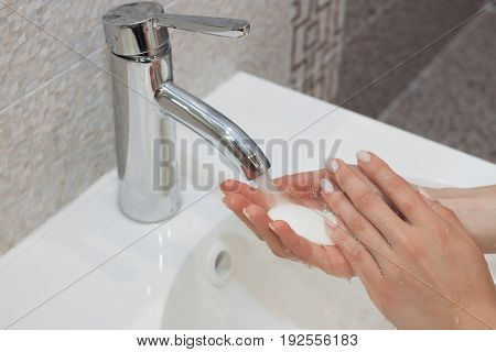 Washing of hands with soap under running water.
