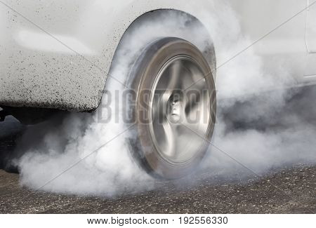 Drag racing car burns rubber off its tires in preparation for the race.