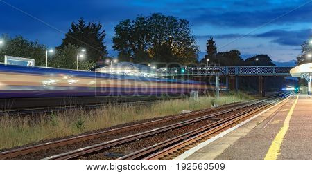 Speeding train through a UK station at night