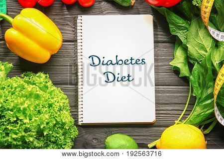 Notebook with text DIABETES DIET and healthy food on wooden background. Health care concept