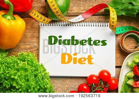 Notebook with text DIABETES DIET and healthy food on wooden background. Health care concept