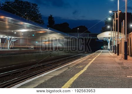 Speeding train through a UK station at night