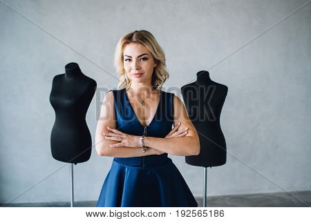 Woman fashion designer in a blue dress is standing near the mannequins. Lips with injection