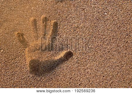 Handprint in the sand and sun set