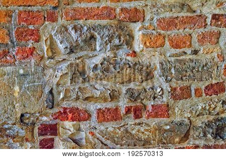 The Wall Built Of Irregular Stones And Bricks Background. Texture Of Old Stonework. Space For Text.