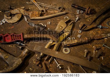 Selection of old worn well used tools on top of an old wooden workbench.