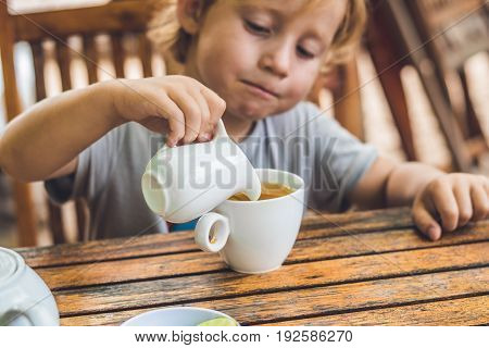 Happy Nice Boy Pours Honey Into The Tea In Summer Green Garden. Portrait. Outdoor