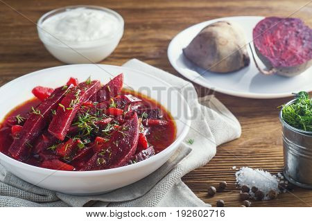 Vegetable soup - red borsch in a white bowl on a rustic wooden background. Healthy beetroot soup vegetarian food. Delicious beet soup with sour cream.