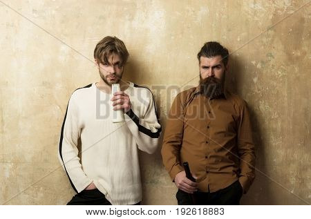 Two Serious Friends In Casual Wear Standing With Bottles