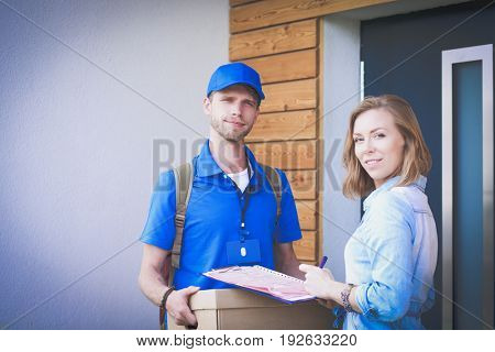 Smiling delivery man in blue uniform delivering parcel box to recipient - courier service concept