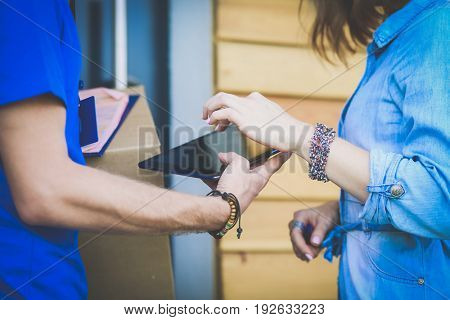 Smiling delivery man in blue uniform delivering parcel box to recipient - courier service concept