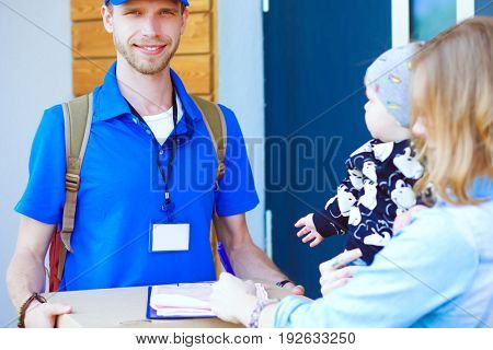 Smiling delivery man in blue uniform delivering parcel box to recipient - courier service concept