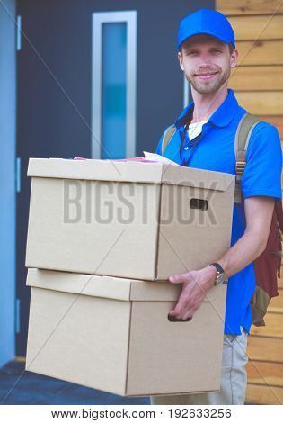 Smiling delivery man in blue uniform delivering parcel box to recipient - courier service concept
