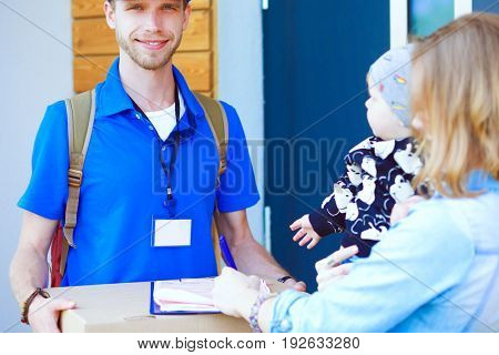 Smiling delivery man in blue uniform delivering parcel box to recipient - courier service concept