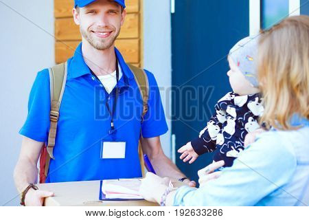 Smiling delivery man in blue uniform delivering parcel box to recipient - courier service concept