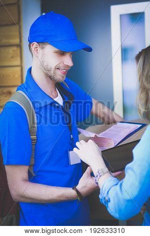 Smiling delivery man in blue uniform delivering parcel box to recipient - courier service concept
