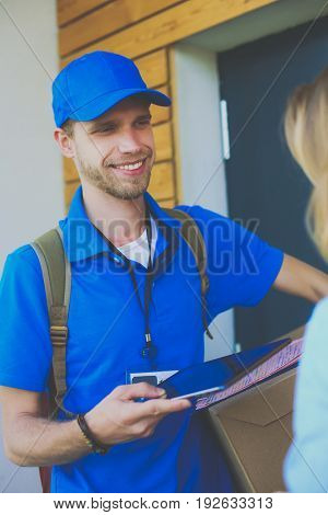 Smiling delivery man in blue uniform delivering parcel box to recipient - courier service concept