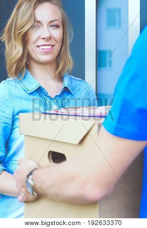 Smiling delivery man in blue uniform delivering parcel box to recipient - courier service concept