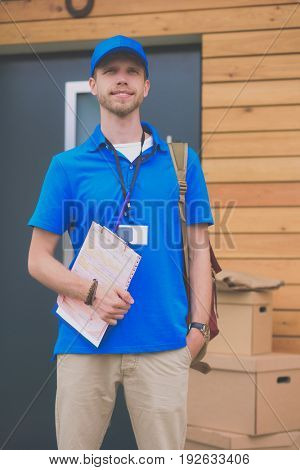Smiling delivery man in blue uniform delivering parcel box to recipient - courier service concept