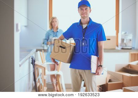 Smiling delivery man in blue uniform delivering parcel box to recipient - courier service concept