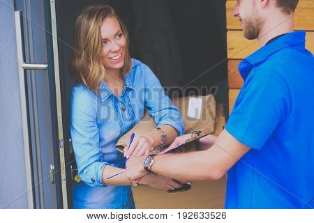 Smiling delivery man in blue uniform delivering parcel box to recipient - courier service concept
