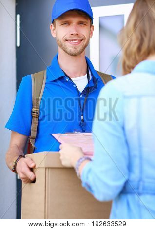 Smiling delivery man in blue uniform delivering parcel box to recipient - courier service concept