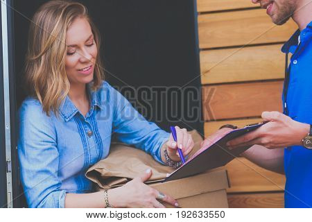 Smiling delivery man in blue uniform delivering parcel box to recipient - courier service concept
