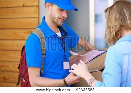 Smiling delivery man in blue uniform delivering parcel box to recipient - courier service concept